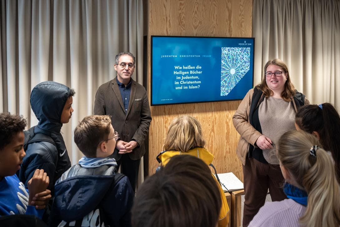 Osman Örs und Patricia Böckmann, Bildungsreferenten, spielen mit Schülerinnen und Schülern ein Religionsquiz.