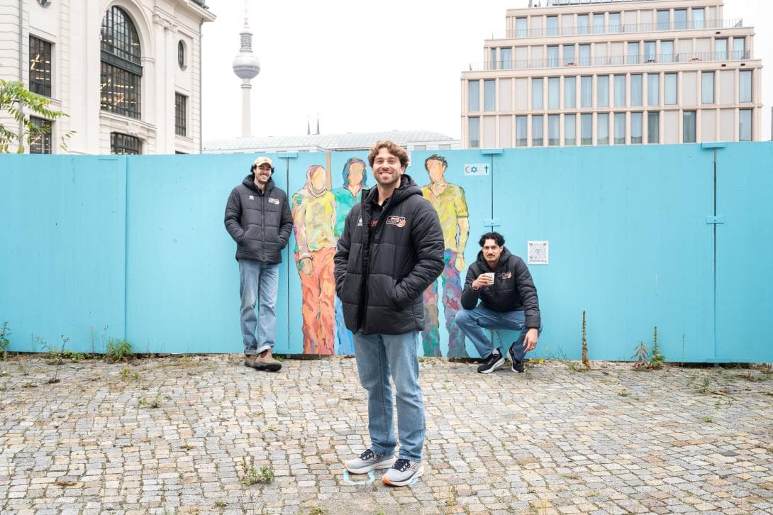 Nolan Flexen, Kyle Dagostino und Nehmiah Mote, Profi-Spieler des Volleball-Rekordmeisters BR Volleys vor dem Insta-Spot auf dem Bauzaun der House of One-Baustelle. 