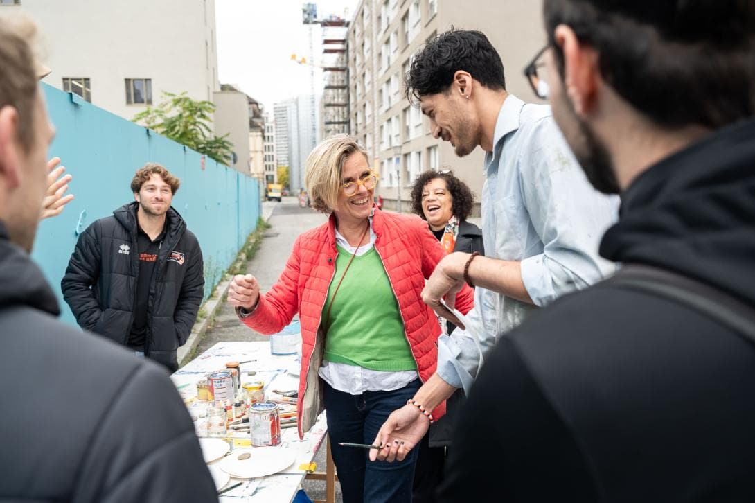 Die Künstlerin Andrea Wallgren unterstützt Kyle Dagostino und Nehamiah Mote beim Entwickeln ihrer Friedensbotschaft, die auf den Zaun gemalt wird. 